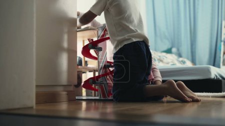 Foto de Niño involucrado en el juego en el dormitorio con parlot estructura de juguete en el suelo - Imagen libre de derechos