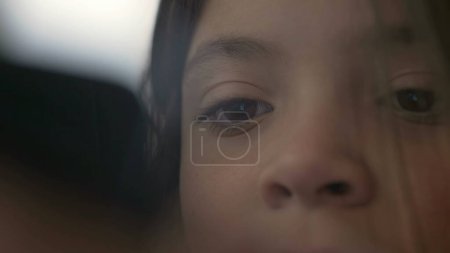 Close-up of child's eyes staring at phone screen consuming media online. Little girl eyesight hypnotized by modern technology looking at smartphone device