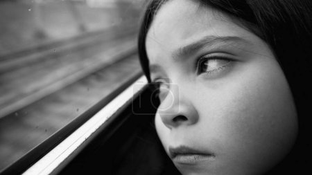 Téléchargez les photos : Triste enfant déprimé regardant depuis la fenêtre du train depuis le siège passager. Gros plan enfant féminin se sentant redouté et mélancolique en noir et blanc, monochrome - en image libre de droit