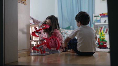 Foto de Hermano y hermana jugando en colaboración con el juguete del estacionamiento, escena del dormitorio cándida - Imagen libre de derechos