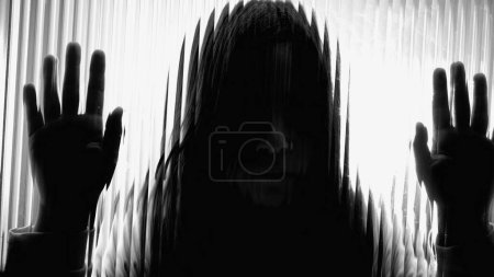 Photo for Silhouette of one Sad child struggling with mental illness leaning on defocused glass window. Little girl depiction of depression in childhood, monochromatic black and white - Royalty Free Image