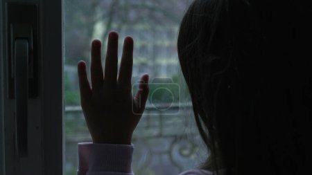 Photo for Close-up child hand leaning on glass window at home staring outside depicting childhood solitude and loneliness - Royalty Free Image