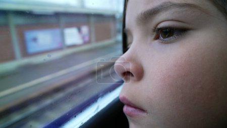 Photo for Thoughtful child close-up face leaning on train window staring at platform station arrival. Macro close-up of contemplative 8 year old little girl arriving at destination - Royalty Free Image