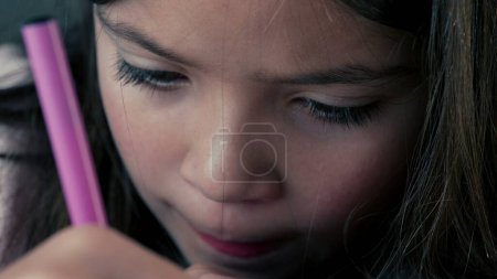 Photo for Concentrated Child Drawing with Coloring Pen - Tight Face Close-up. A child deeply focused on drawing on paper - Royalty Free Image