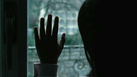 Téléchargez les photos : Moody Représentation de l'enfant avec dépression, fille penchée sur la fenêtre contemplant dans la solitude - en image libre de droit
