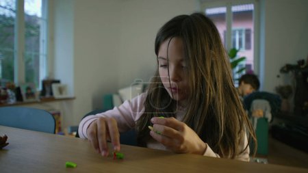 Téléchargez les photos : Petite fille concentrée sur l'assemblage de jouets, 8-year-old Engrossed in Play - en image libre de droit