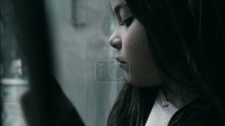 Photo for One depressed child feeling sad and lonely leaning on glass. Close-up face of a little girl struggling with depression in childhood - Royalty Free Image