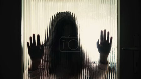 Photo for Depressed child leaning on defocused glass, depicting childhood mental health issues. Silhouette of 8 year old little girl - Royalty Free Image