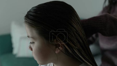 Foto de Padres peinando el cabello del niño en la rutina nocturna antes de acostarse, primer plano de la cara de la niña mientras la madre peina el cabello - Imagen libre de derechos