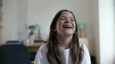 Téléchargez les photos : Une petite fille heureuse éclate de rire à haute voix. Gros plan visage d'enfant se sentant joie dans un moment insouciant, authentique vraie vie rire et sourire - en image libre de droit
