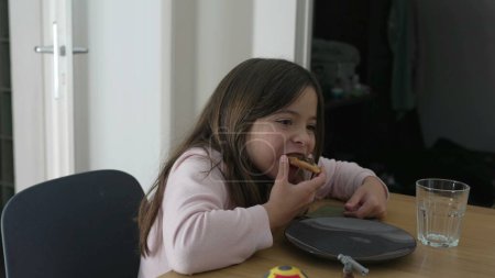 Ein kleines Mädchen beim Essen interagiert außerhalb der Kamera mit der Familie. Kind nascht Efiha