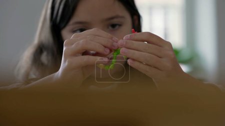 Foto de Pequeña niña concentrada absorbida en el juego creativo por el montaje de objetos. Niño de 8 años jugando solo, actividad de ocio infantil - Imagen libre de derechos