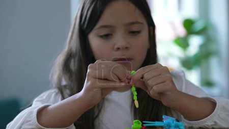 Foto de Niña de ocho años enfocada en el montaje de juguetes, primer plano detallado de la concentración lúdica del niño - Imagen libre de derechos