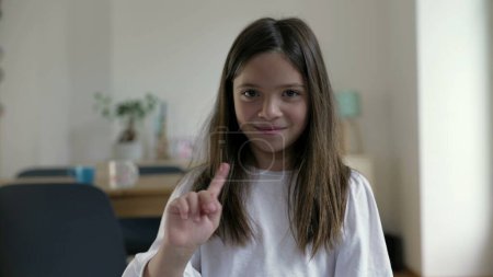 One small girl rejecting offer by shaking finger to viewer while smiling. Child defending accusation by waving hand saying NO