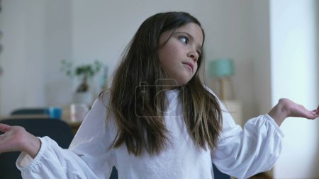Téléchargez les photos : Une petite fille confus avec une expression déroutée sans savoir quoi faire, enfant indécis de 8 ans avec portrait perplexe - en image libre de droit
