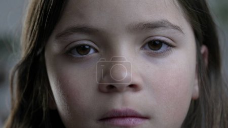 Foto de Macro apretado primer plano de la cara del niño mirando a la cámara con expresión en blanco solemne. Retrato de niña - Imagen libre de derechos