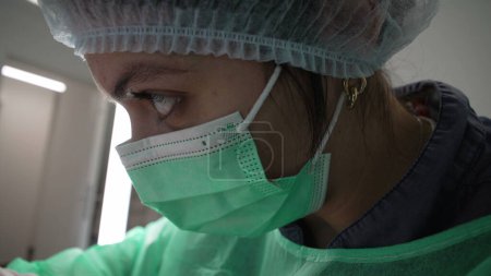 Photo for Close-up Female Dentist concentrated at work, wearing antiseptic attire. Dental professional in deep focus, macro close-up profile face - Royalty Free Image