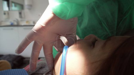 Téléchargez les photos : Dentiste traitant les dents de l'enfant à la clinique dentaire. Personnel de santé de la femme médecin s'occupant de l'hygiène buccodentaire du patient - en image libre de droit