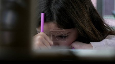 Photo for Little Girl Intensely Engaged in Artistic Drawing - Face Close-up. A young girl completely absorbed in drawing with a coloring pen - Royalty Free Image