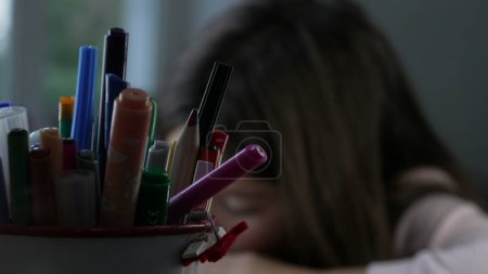 Photo for Coloring pens inside bucket in foreground with little girl in blurred background grabbing a pen during creative drawing session - Royalty Free Image