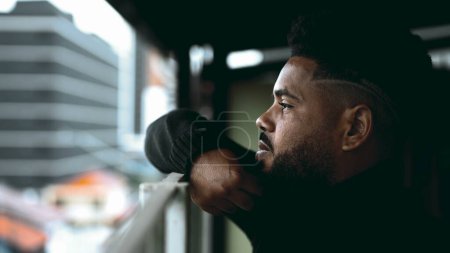 Photo for Introspective South American Young Man Gazing from Balcony - Deep Mental Reflection of 20s Black Male on Life's Challenges - Royalty Free Image