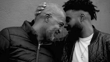 Photo for Emotional Embrace Between African American Father and Adult Son, Foreheads Together in Affectionate Hug in black and white monochrome, family warmth and care - Royalty Free Image