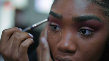 Foto de Cara de cerca de una joven latina negra se aplica maquillaje delante del espejo, chica adulta de 20 años de ascendencia africana se prepara para salir - Imagen libre de derechos