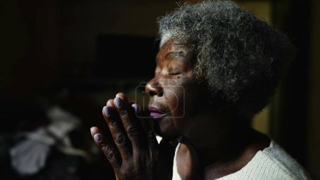 Téléchargez les photos : Femme chrétienne fervente et afro-américaine âgée dans la PRIÈRE à la maison, visage en gros plan d'une dame noire âgée de 80 ans fermant les yeux dans la méditation profonde, l'espoir et la foi - en image libre de droit