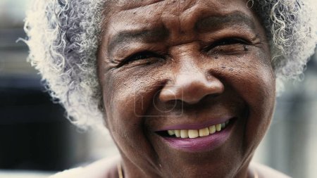 Photo for Charismatic Portrait of a black senior woman smiling at camera depicting old age in 80s. Friendly happy elderly African American person with wrinkles and gray hair - Royalty Free Image