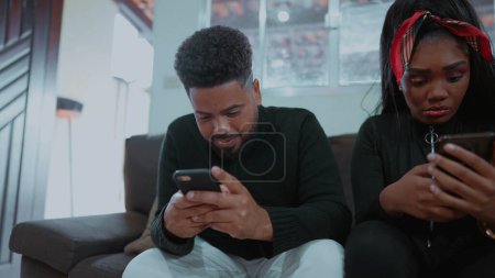 Photo for Friends isolated from each other by looking at cellphone devices seated at home sofa, mother and young adult children absorbed by technology addiction, social disconnection and loneliness - Royalty Free Image
