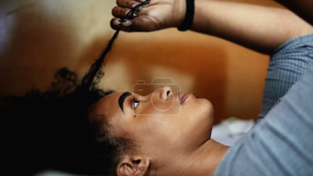 Foto de Una joven contemplativa latina latina adulta juega con el cabello mientras sueña despierto y expresión reflexiva puesta en la cama contemplando la decisión de ponderación del techo - Imagen libre de derechos