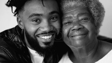 Fröhliche Generationenporträts Ältere Großmutter in den Achtzigern mit lächelndem erwachsenem Sohn in den Zwanzigern, monochrom schwarz-weiß