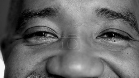 Photo for Macro close-up of a senior middle-aged man eyes with wrinkles and mouth smiling, person of African descent feeling happy - Royalty Free Image
