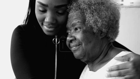 Fürsorglicher afroamerikanischer Teenager, der zärtlich eine ältere Großmutter mit grauen Haaren hält, Familie und Generationenbindung in künstlerischem Schwarz-Weiß zelebriert