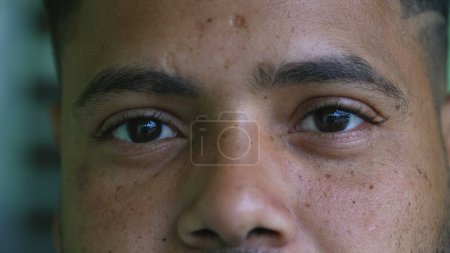Photo for One serious young black latin hispanic man close-up eyes staring at camera with solemn expression. South American Brazilian person eye to eye stare - Royalty Free Image
