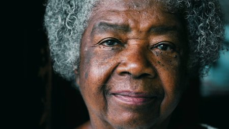 Téléchargez les photos : Une dame âgée noire sérieuse regardant la caméra montrant l'expérience et la sagesse. Afro-Américain senior années 80 femme avec rides et cheveux gris portrait visage gros plan - en image libre de droit