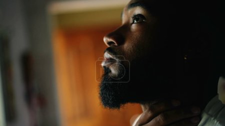 Photo for One pensive worried young black man closeup face standing by window. African American person touching face feeling preoccupied and anxious about life's decision - Royalty Free Image