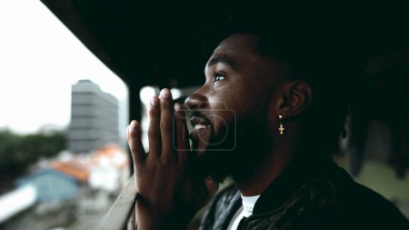 Téléchargez les photos : Un jeune homme noir spirituel en prière méditative profonde, contemplative 20s afro-américaine ouvrant les yeux et souriant avec espoir et foi. CONCEPTION DE GRATITUDE - en image libre de droit