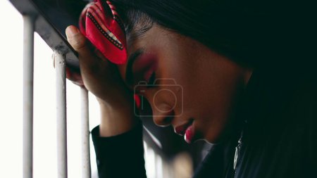 Photo for One worried young black woman with eyes closed leaning on metal bar feeling sad struggling with setback, profile close-up face of latin person of African descent feeling down in luck - Royalty Free Image