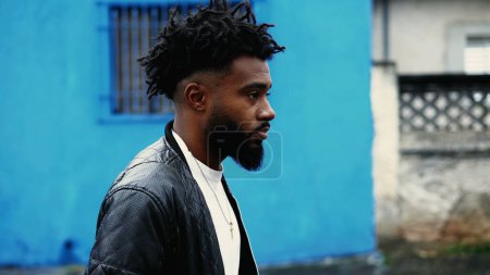 Ein junger schwarzer Mann geht in der Stadt vorwärts, Nahaufnahme von Afroamerikanern in den 20er Jahren mit nachdenklichem Blick