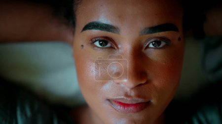 Foto de Una joven latina negra abre los ojos y mira directamente a la cámara y sonríe exudando confianza y despertar. persona afroamericana de 20 años - Imagen libre de derechos
