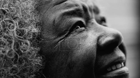 Foto de Arrugada agradecida Senior mujer afroamericana cerrando los ojos en oración y meditación en blanco y negro. Una anciana y esperanzada dama negra de 80 años sintiéndose FIEL mirando hacia arriba - Imagen libre de derechos