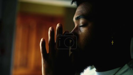 Profil Nahaufnahme eines jungen schwarzen Mannes, der zu GOTT betet. Meditativer Afroamerikaner mit geschlossenen Augen, der sich mit Hingabe beschäftigt