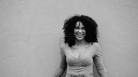 Photo for Charismatic African American young woman laughing and smiling in black and white. Happy joyful 20s person of African descent in monochrome - Royalty Free Image