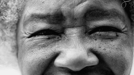 Foto de Macro primer plano de una mujer mayor de color negro arrugado ojos mirando la cámara que representa la vejez y la sabiduría en blanco y negro. Afro-americano detalle cara - Imagen libre de derechos