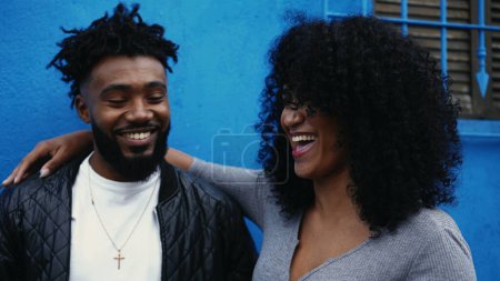Téléchargez les photos : Jeunes Afro-Américains heureux souriant et riant debout à l'extérieur dans un cadre urbain. Un joyeux couple noir véritable rire - en image libre de droit