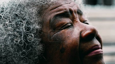 Photo for Macro close-up of a wrinkled aged Mature black woman with gray hair in 80s closing eyes in meditation gazing up at sky with PEACE and TRANQUILITY - Royalty Free Image