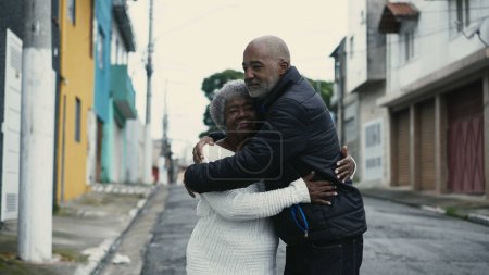 Photo for Loving Embrace of African American Son with Elderly Mother on City Street, Genuine Care Between 80s Senior and Her Caretaker - Royalty Free Image