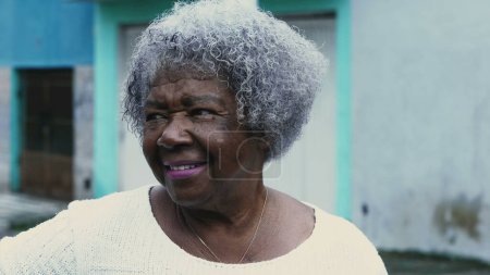 Photo for One happy black Brazilian senior lady with gray hair standing in street outside smiling at camera, tracking shot of African American woman in 80s close-up face - Royalty Free Image
