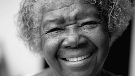 Photo for One happy black senior woman in 80s in black and white. Monochromatic portrait of wise older African American lady smiling at camera showing old age and wisdom - Royalty Free Image